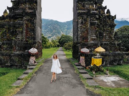 Tourist woman posing near Traditional Balinese Hindu gate Candi Bentar close to Bedugul, Bratan lake...