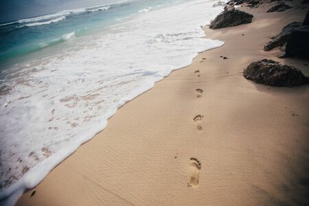 Footprints in wet sand of paradise beach,travel concept,Bali,Indonesiaの写真素材