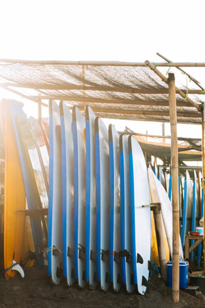 Stack of blue and white color soft surfboards in a stack by ocean.Bali.Indonesia. Surf boards on sandy beach for rent. Surf lessons on Canggu beach.の写真素材