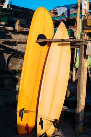 Retro two yellow surfboards for rent on the beach. Multicolored surf boards different sizes on stand in rental place on Bali, Indonesiaの写真素材