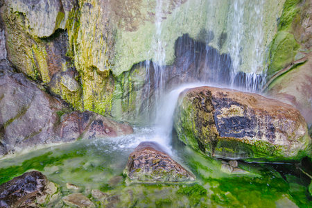 Waterfall in the forest with mossy rocks and clear water.の写真素材