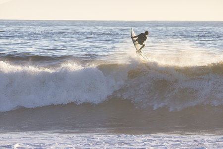 Surfer on the beach at sunset in Santa Cruz, California.