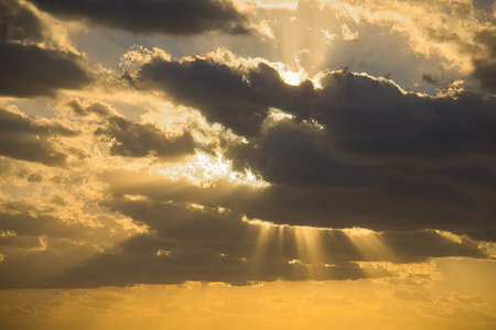 Sunset sky with clouds and sunbeams in the evening.