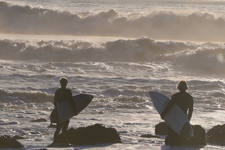 Surfers with surfboards on the beach at sunset in Californiaの写真素材