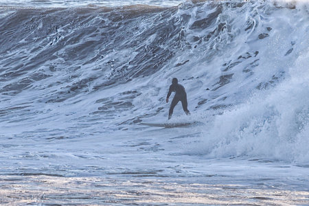 Surfer on a surfboard in the waves at sunset, California