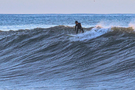 Surfer on the ocean wave at sunset in Bali, Indonesia