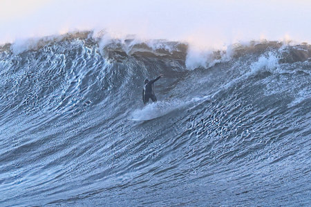 Surfer surfing ocean wave on a sunny day in winter season.