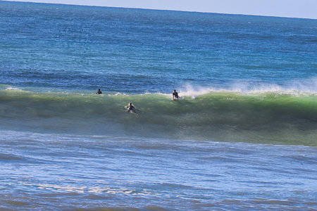 Surfers at the beach of Atlantic ocean in Nazare, Portugal