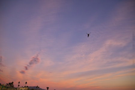 Silhouette of a helicopter flying in the sky at sunset.の写真素材