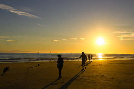 Silhouette of people walking on the beach at sunset time.