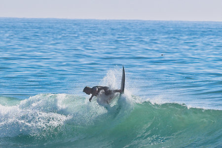 Surfer jumping into the ocean with a surfboard in the background