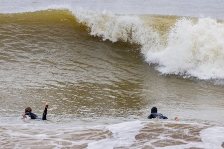 Two surfers enjoying the waves at the beach on a sunny day