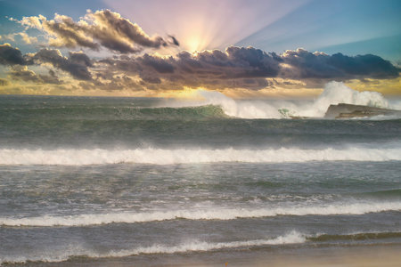 Waves breaking on the beach at sunset, North Shore, New Zealand