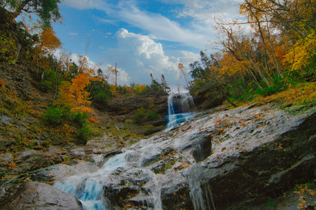 Waterfall in the autumn forest. Colorful foliage in the forest.