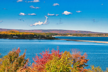 Autumn view of lake with colorful trees and blue sky with cloudsの写真素材