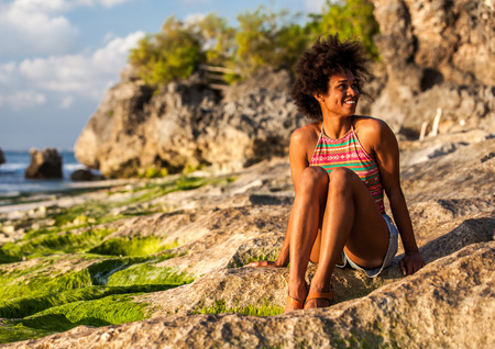 Girl looking at waves on Padang Padang beach, Bali, Indonesia at sunsetの写真素材