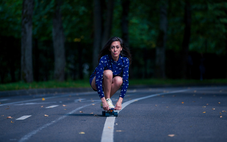 Girl skating pennyboard in the middle of the asphalt road in the parkの写真素材