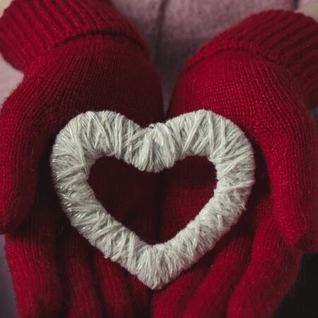 A girl in red gloves holds a heart.の写真素材