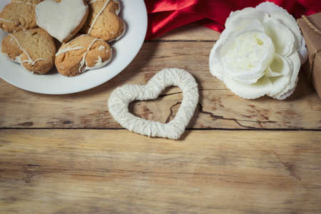 Valentine's day composition. Biscuits hearts, rose flower and heart handmade on wooden background.の写真素材