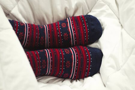 Female legs in socks with ornament in bed. Top view.