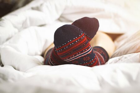 Legs of a girl in socks against the background of a bed.の写真素材