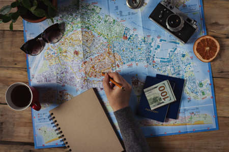 Travel concept. Female hand marks the spot on the map. Top view.