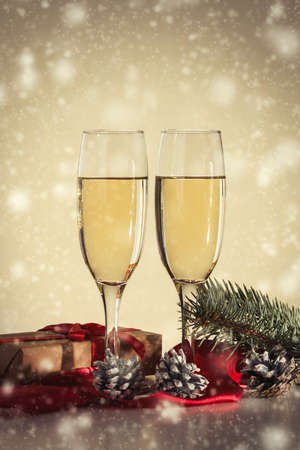 Ð¡oncept of Christmas and New Year. Two glasses with champagne, a gift and fir cones. Snowfall.の写真素材