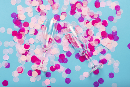 Pink confetti and empty portions for champagne on a blue background. Party and holiday concept. Flat lay, top view.の写真素材