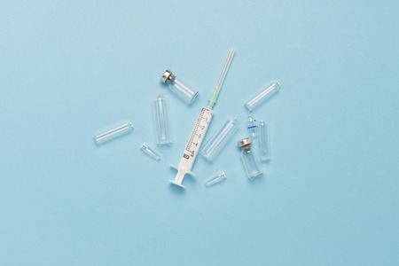 Empty ampoules and syringe on a blue background. Concept of dependence on medical drugs, drug...