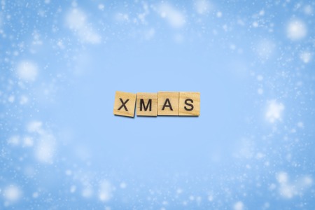 Text Xmas laid out of wooden plates with letters on a blue background with snow. Concept of Happy Christmas and Happy New Year. Minimalism. Flat lay, top view.の写真素材