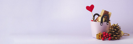 Small plastic bag for shopping, gift boxes, heart on a stick, red alarm clock,  Christmas decorations,  violet background. Concept of pre-holiday shopping, sale, Black Friday, Cyber Monday. Banner.の写真素材