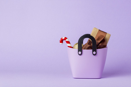 Small plastic bag for shopping, gift boxes, heart on a stick, purple background. Concept of pre-holiday shopping, gifts for friends and relatives, Christmas sale, Black Friday, Cyber Monday.の写真素材