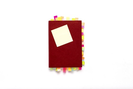 Red diary with stickers on the pages on white background. Concept of a successful business, a lot of...