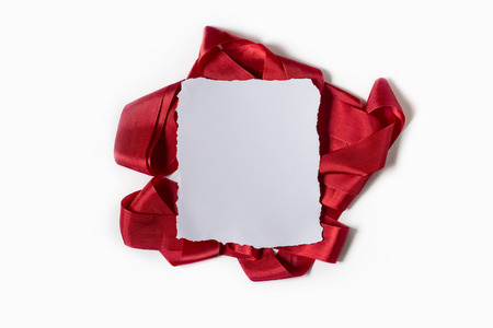 Blank sheet of paper. Red ribbon on white background. Flat lay.