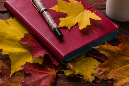 Red diary and pen on a wooden table.の写真素材