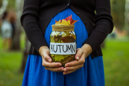 Girl with a glass jar with autumn leaves in hands.の写真素材