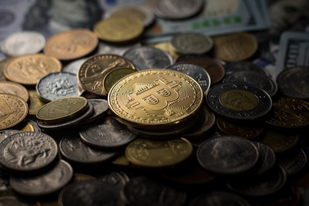 Bitcoin on a pile of coins from different countries around the world. Dollar, Euro, Ruble, Hryvnia. Beautiful Game of Light and Shadows.の写真素材