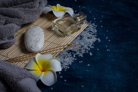 Spa concept. Towel, soap, Hawaiian Plumeria Flower, Sea salt, bottles of perfume on a blue...