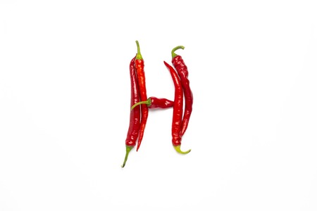 Red hot chile pepper lined in the letter H on a white background. Flat lay, top view.