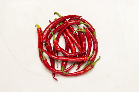 Red hot Chilean pepper lined in a circle shape on a white stone background. Flat lay, top view.の写真素材