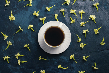 Cup of coffee and flowers on a dark blue background. Flat, top view.の写真素材