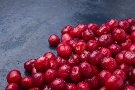 Freshly picked cherries with drops of dew and water on a dark blue stone background. The concept of harvesting. Flat lay, top view.の写真素材