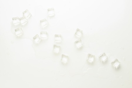 Cubes of ice and spilled water on a light background.の写真素材