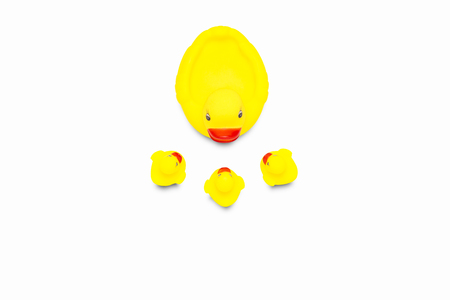 Rubber toy of yellow color Mama duck and small ducklings on a white background. The concept of maternal care and love for children. Flat lay, top view.の写真素材