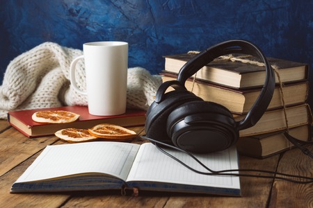 Books are stacked, Headphones, White Cup, Orange Slices, open Diary on a wooden background. The Concept of Audio Books and Audio Education.の写真素材