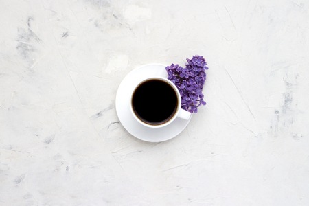 White cup with a coffee and beautiful lilac flowers on a white background. Top view, flat, lay, copy spaceの写真素材