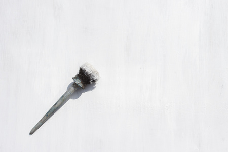 Paint brush in white paint on a wooden background painted white. Flat lay, top view.の写真素材