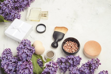Accessories for make-up and skin care, perfumes, lilacs on a light stone background.の写真素材