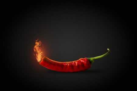 Red hot Chili pepper with fire coming out of it. Dark Black Background. Concept of very hot pepper.の写真素材