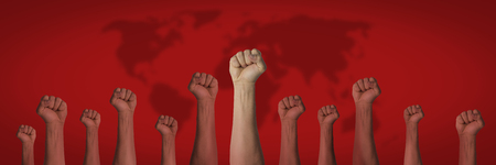 Hands raised up and closed in a fist on a red background with a map of the earth. Concept of unity of the people, revolution, revolt, riot. Banner.の写真素材